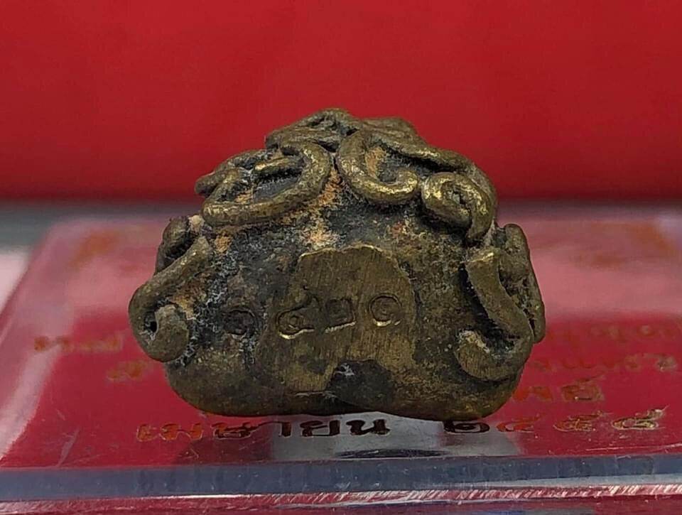 Borom Kru Phu Phu Ruesi Amulet Wealth Calling Edition small antique brass charm with ornate curls on red display