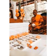 Buddhist protection amulet Thailand on display with a monk in an orange robe in a serene temple setting
