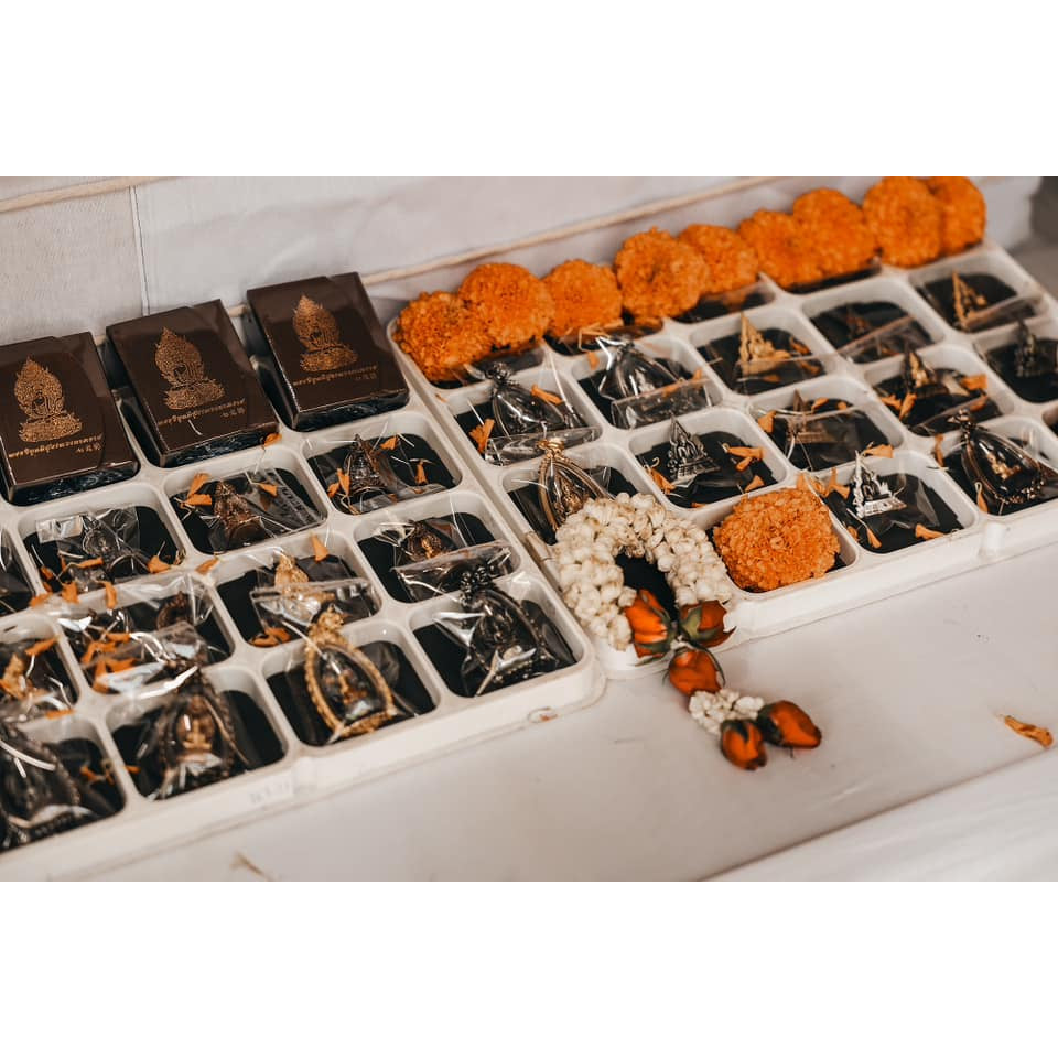 Variety of Buddhist protection amulet Thailand displayed in trays, featuring intricate designs and offerings