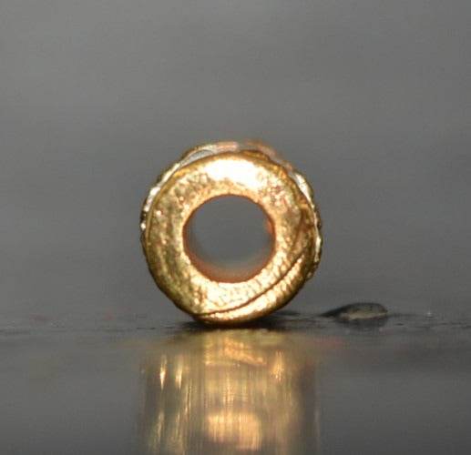 Close-up of a gold charm and attraction Thai talisman featuring a hollow design for spiritual use