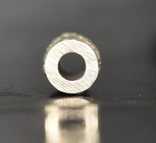 Close-up of a silver charm and attraction Thai talisman with intricate detailing and a hollow center