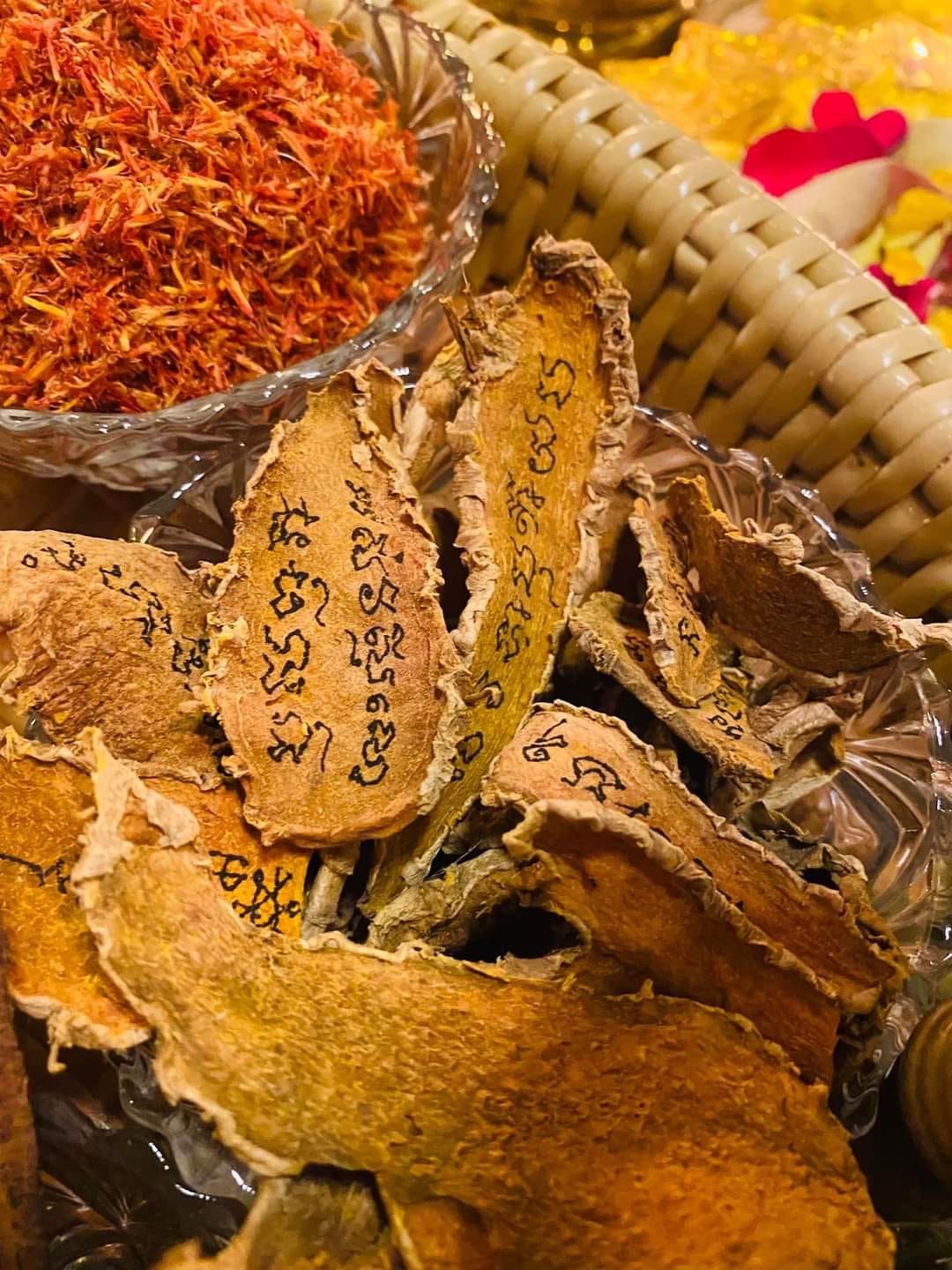 Thai amulet for cleanse negative energy featuring dried herbs and inscriptions in decorative bowl