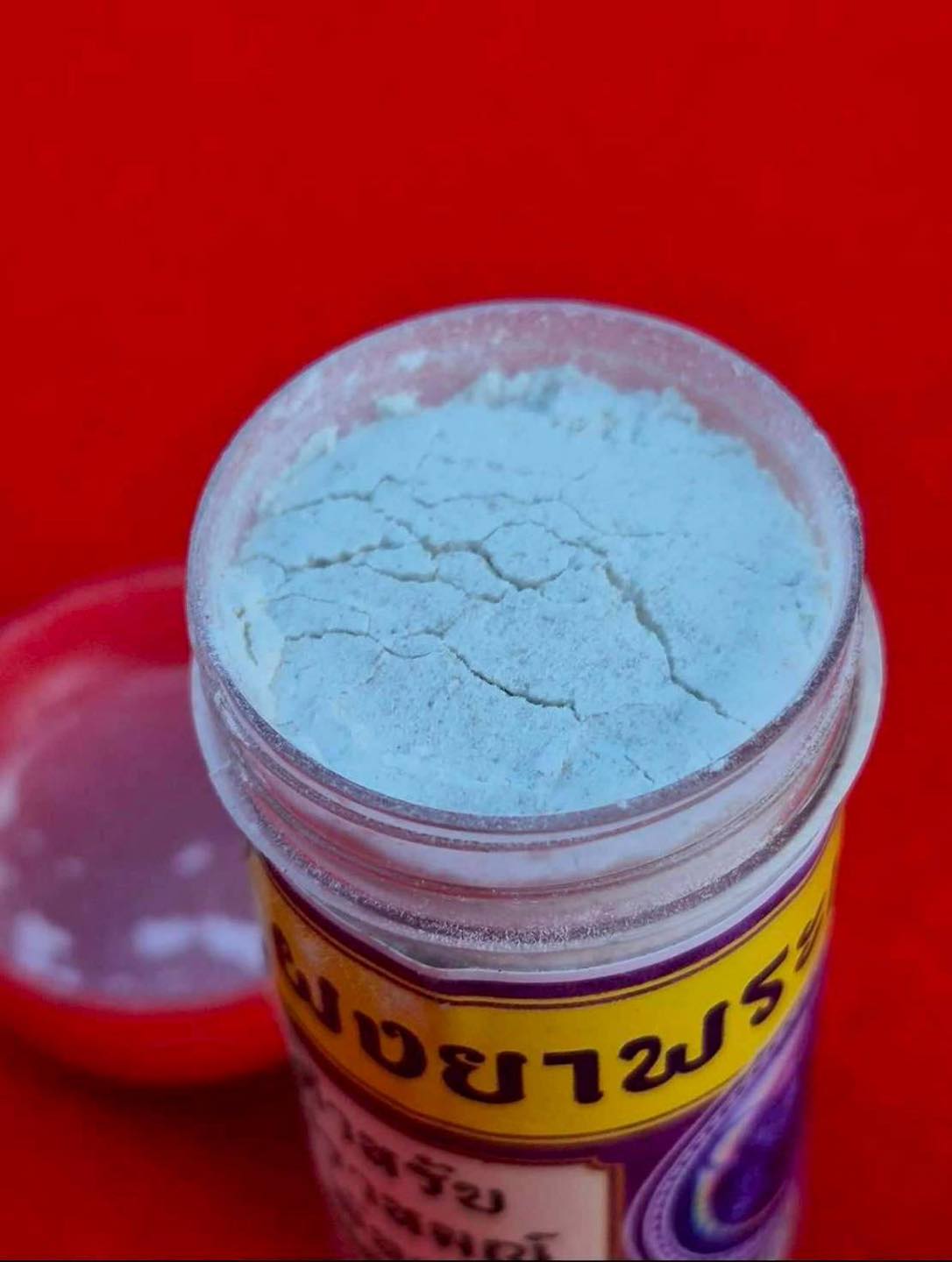 Thai Blessing Co cleanse negative energy Thai amulet powder in a clear jar with a red lid