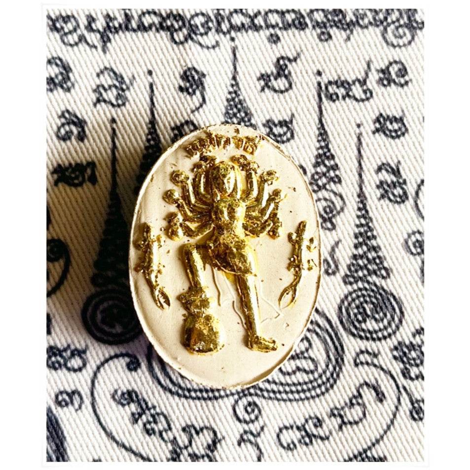 Divine attraction Thai charm featuring a gold statue on a patterned background for positive energy and blessings