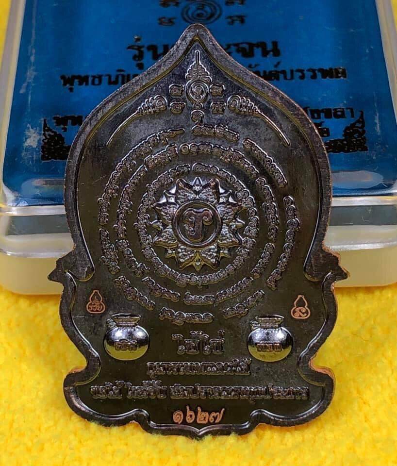 Detailed Ei Khai Phaya Kai bronze amulet with intricate engravings on a yellow surface