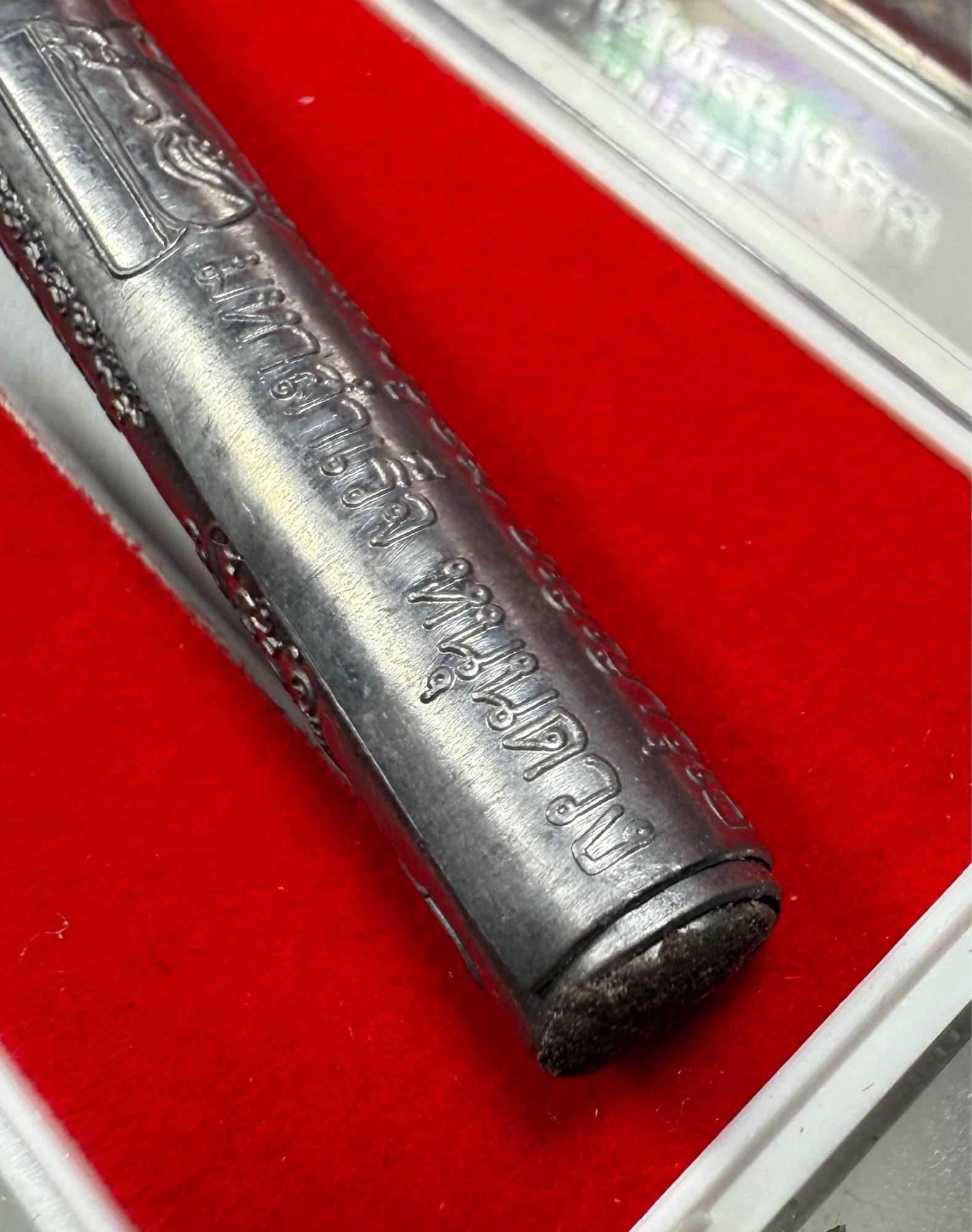 First edition collectible Thai blessing charm engraved metal amulet on red velvet background