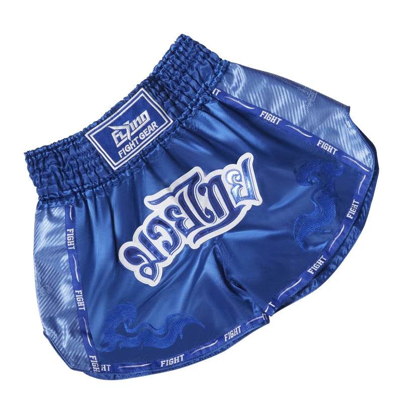 Blue Muay Thai boxing shorts with elastic waist and white Thai script and dragon graphics