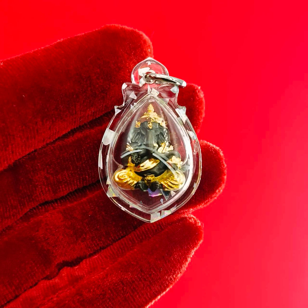 Ganesh amulet for luck and success encased in a clear pendant, detailed craftsmanship visible.
