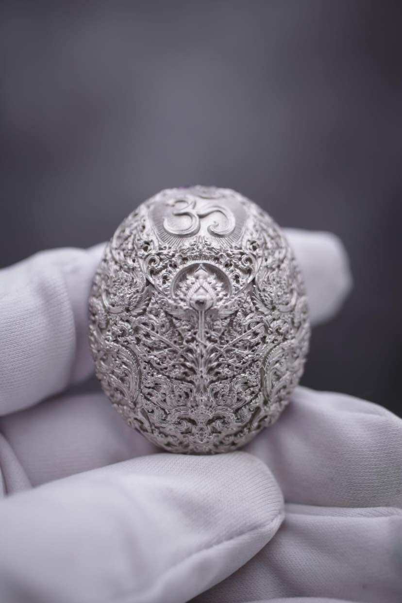 Intricately designed Ganesh coin amulet for wealth held in a gloved hand, symbolizing prosperity
