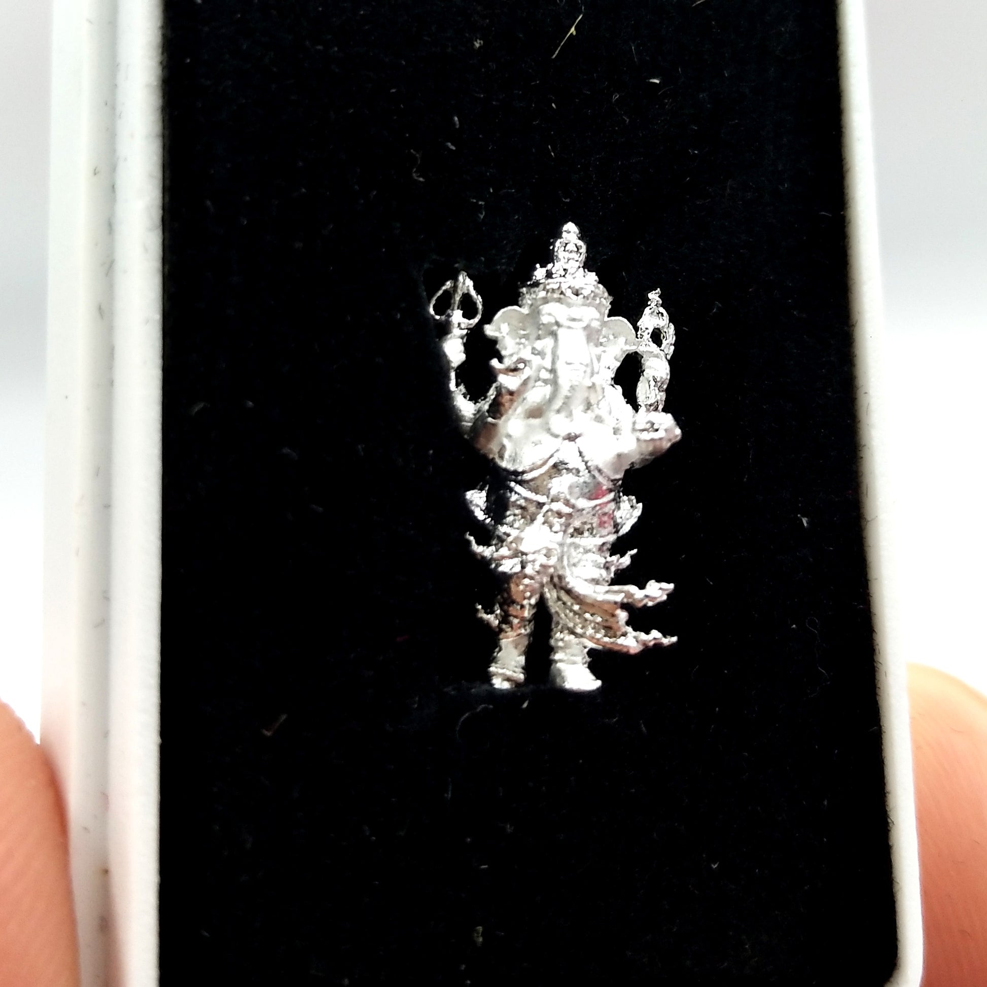 Silver Ganesha amulet for success displayed on black velvet highlighting intricate details