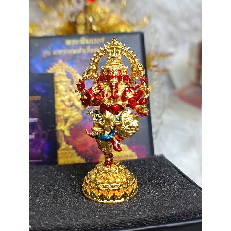 Golden and red Ganesha success fulfillment amulet statue with intricate design on black cushion