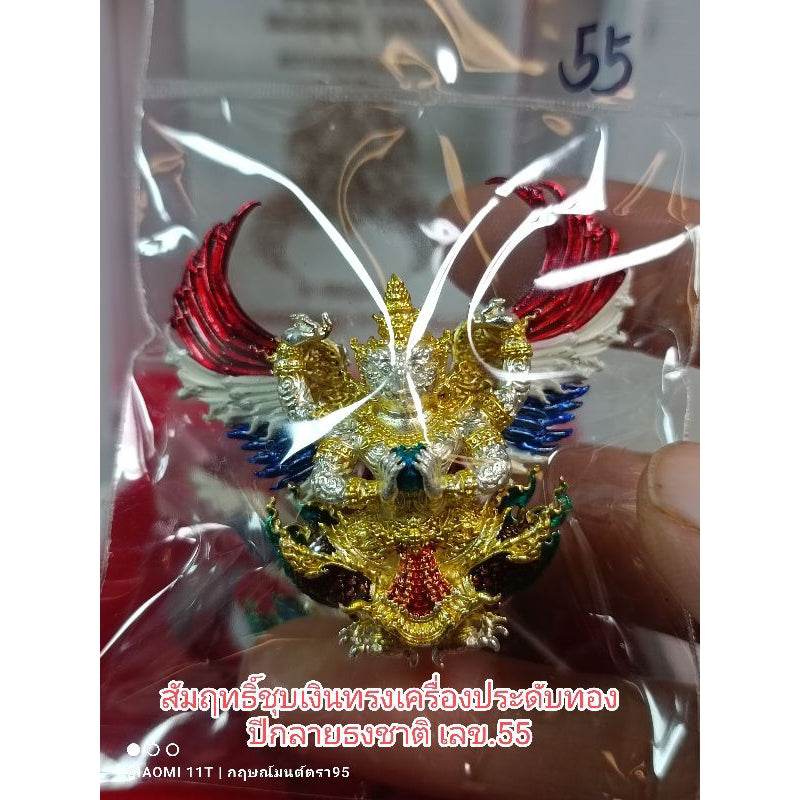 Colorful Garuda amulet from Thailand with gold, red, blue, and green details inside clear packaging