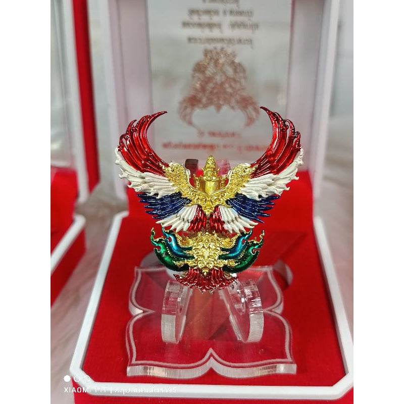 Garuda amulet from Thailand with red white blue and gold detailing in a clear display case