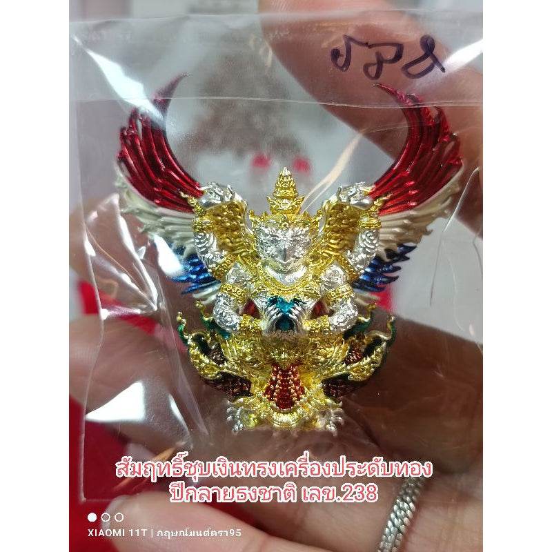 Garuda amulet from Thailand in gold silver and red colors held in hand by Thai Blessing Co