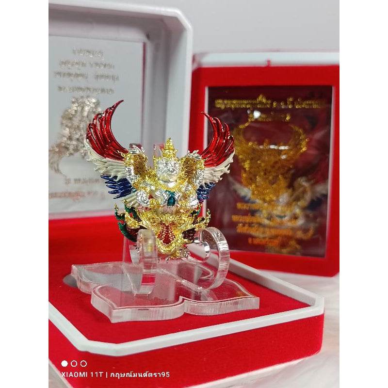 Detailed Garuda amulet from Thailand with red gold and blue accents displayed in a red and white gift box