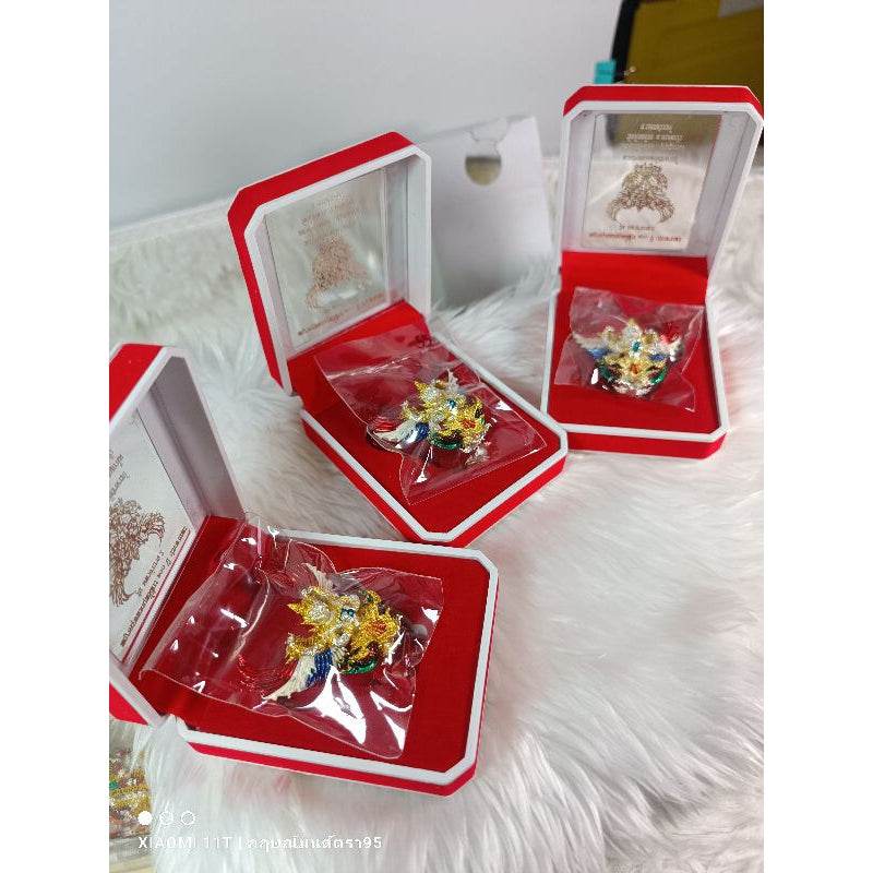 Garuda amulet from Thailand displayed in red and white presentation boxes on white fur surface