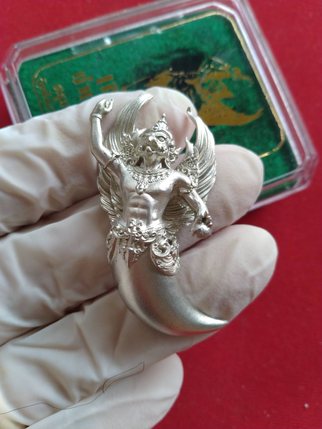Garuda claw pendant blessed by Kruba Virut displayed on a hand with a protective glove