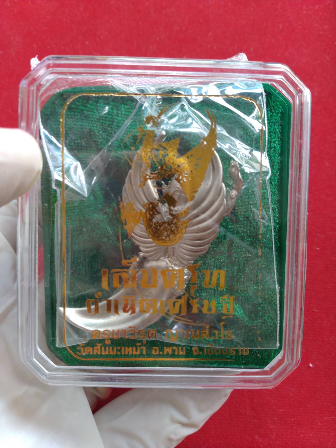 Garuda claw pendant blessed by Kruba Virut in a protective case with green background