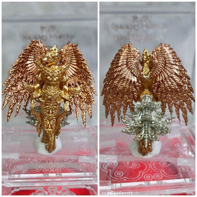 Detailed gold and copper Garuda Parameswara amulet with intricate wings and base displayed in a clear case