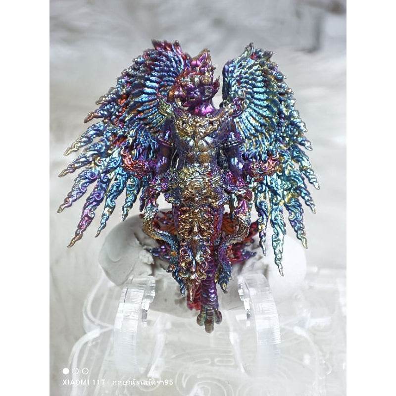 Colorful intricately designed Garuda Parameswara amulet with vibrant blue and purple wings on clear stand