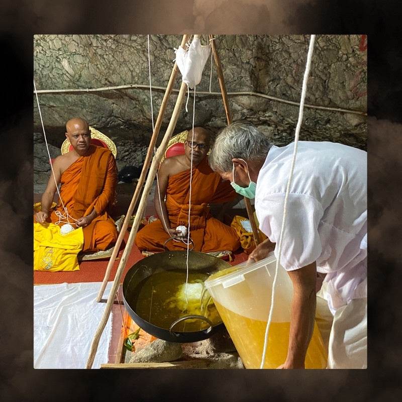 Thai charm oil for prosperity poured into a large brass bowl during a traditional blessing ritual