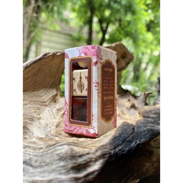 Thai charm oil for prosperity in floral pink box with wooden cap bottle displayed on natural wood background