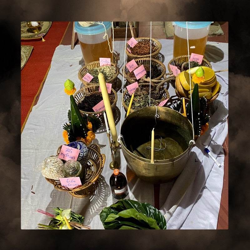 Thai blessing altar with brass bowl candles fruit baskets incense and bottle of Thai charm oil for prosperity