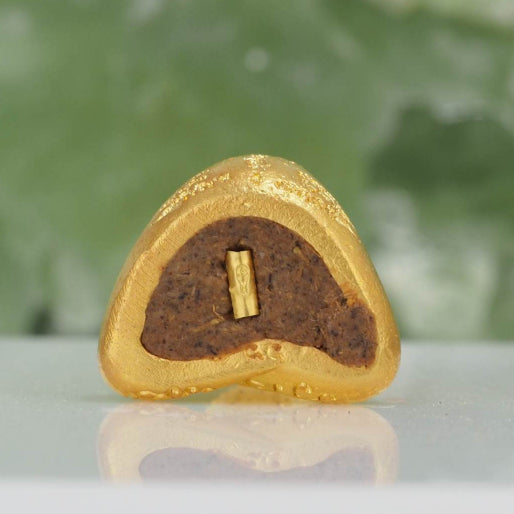 Close-up of a gold-encased Phra Pidta amulet for wealth with intricate details by Thai Blessing Co