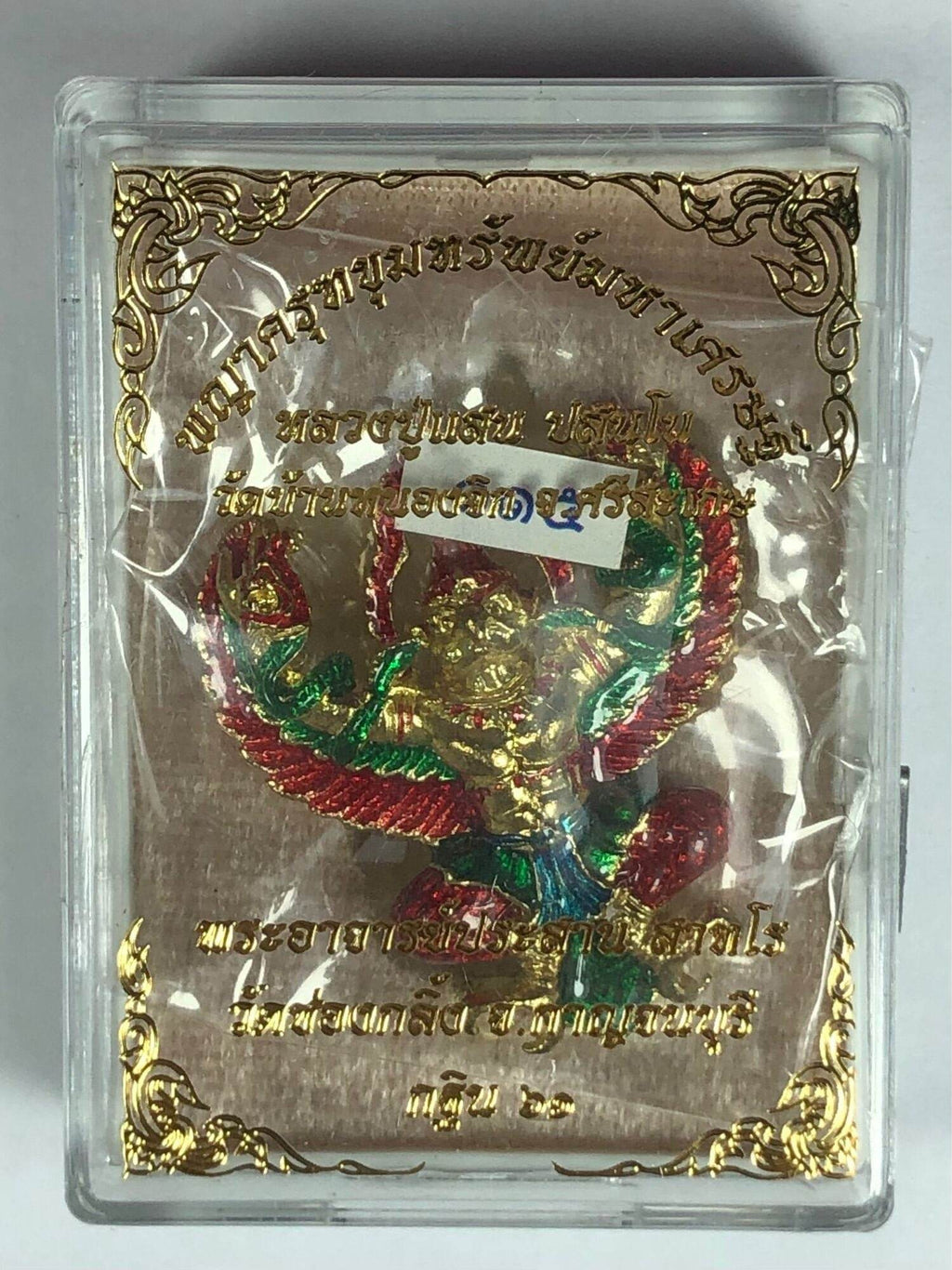 Golden Garuda lucky charm figurine with red and green details in decorative clear display case