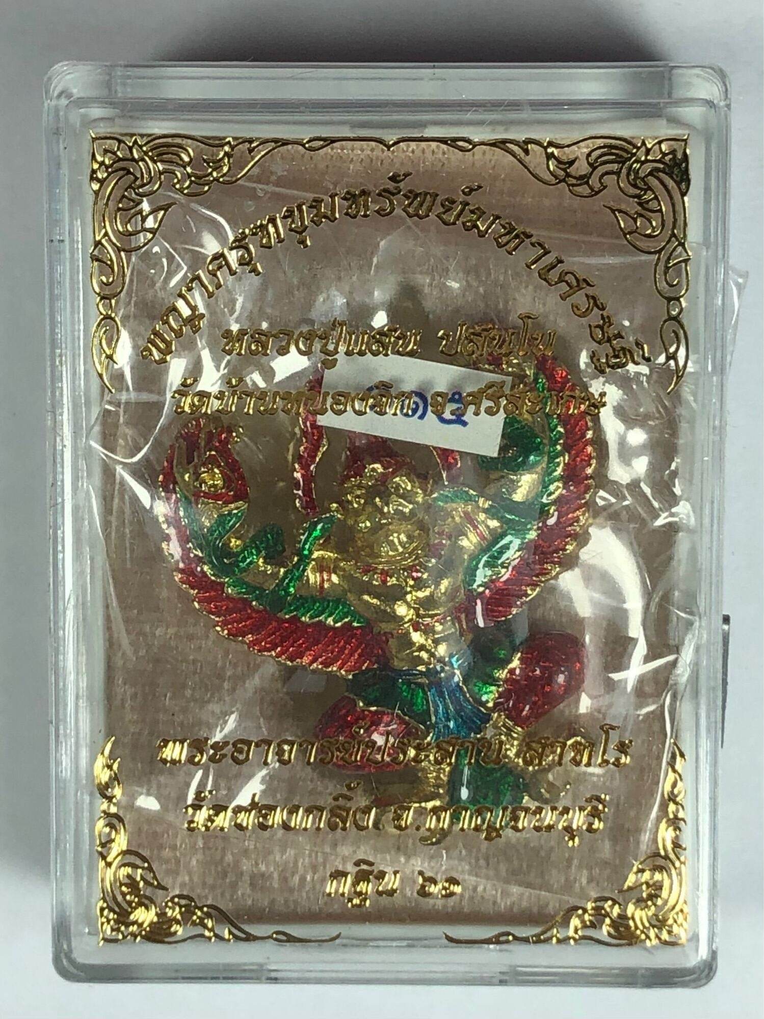 Golden Garuda lucky charm figurine with red and green details in decorative clear display case