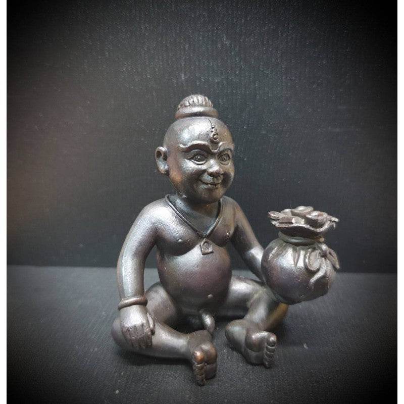 Guardian boy wealth figurine crafted in dark material, holding a pot symbolizing prosperity