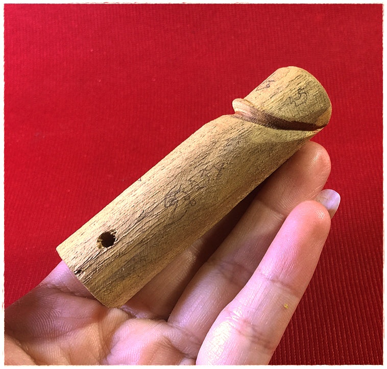 Authentic palad khik amulet held in hand, crafted from natural wood for protection and good fortune