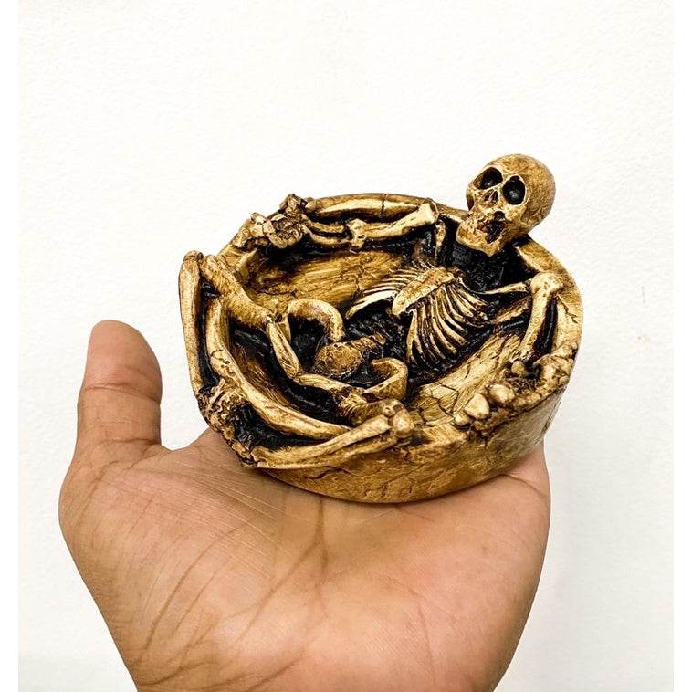 Hand holding a handcrafted resin skeleton ashtray with detailed reclining skeleton design