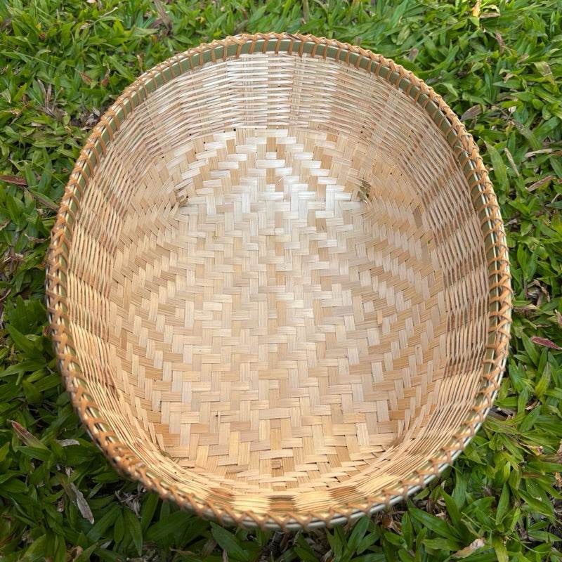 Handmade Thai bamboo basket with intricate weaving pattern placed on green grass