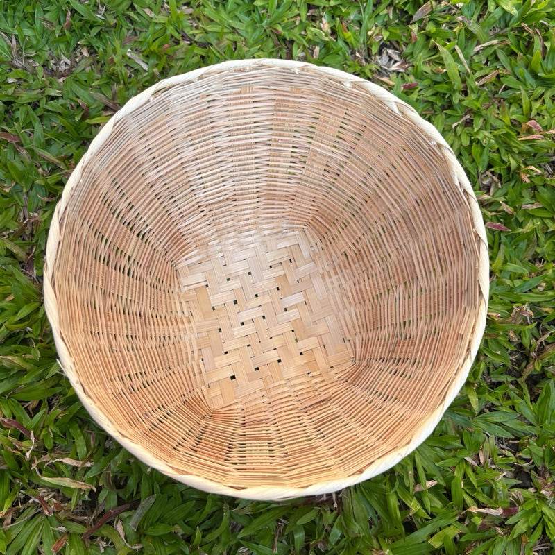 Handmade Thai bamboo basket with woven design placed on green grass background