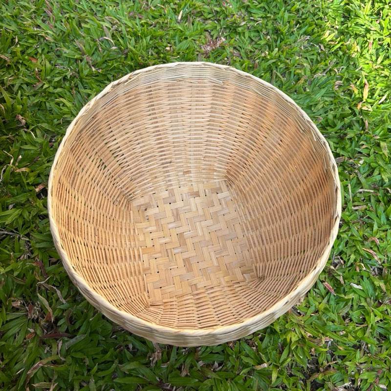 Handmade Thai bamboo basket with natural weaving pattern on green grass background