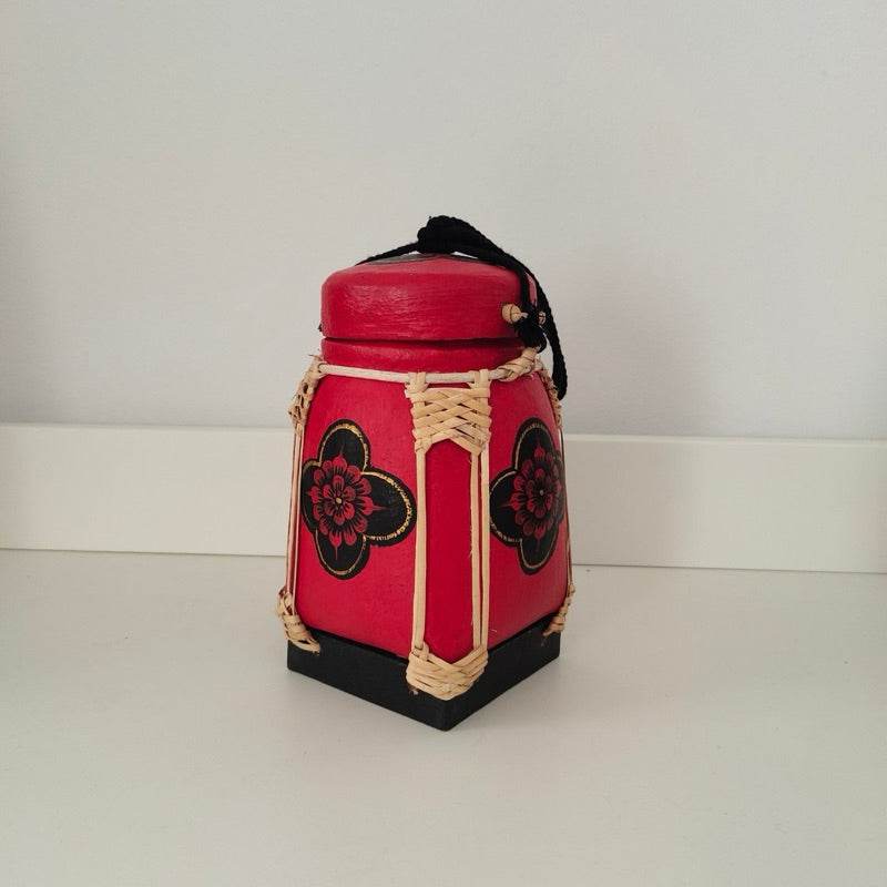 Handmade Thai bamboo rice box in red with black floral patterns and woven details
