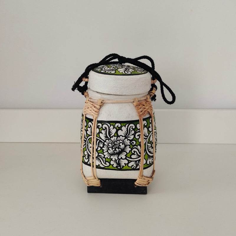 Handmade Thai bamboo rice box with intricate black and white floral design and natural woven accents