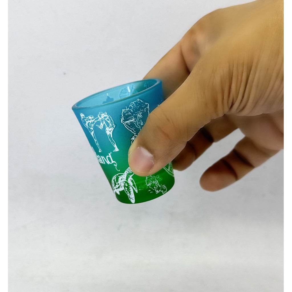 Hand holding a colorful handmade Thailand mini tumbler with white illustrations on blue and green background