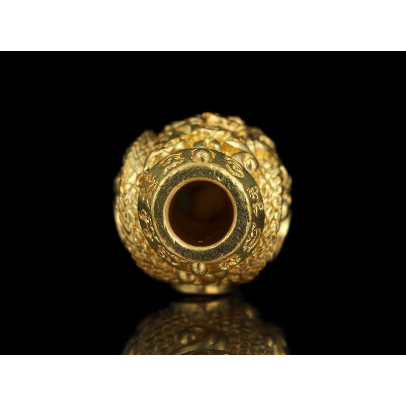 Close-up of Infinity Naga amulet for instant wealth in gold with intricate detailing on black background