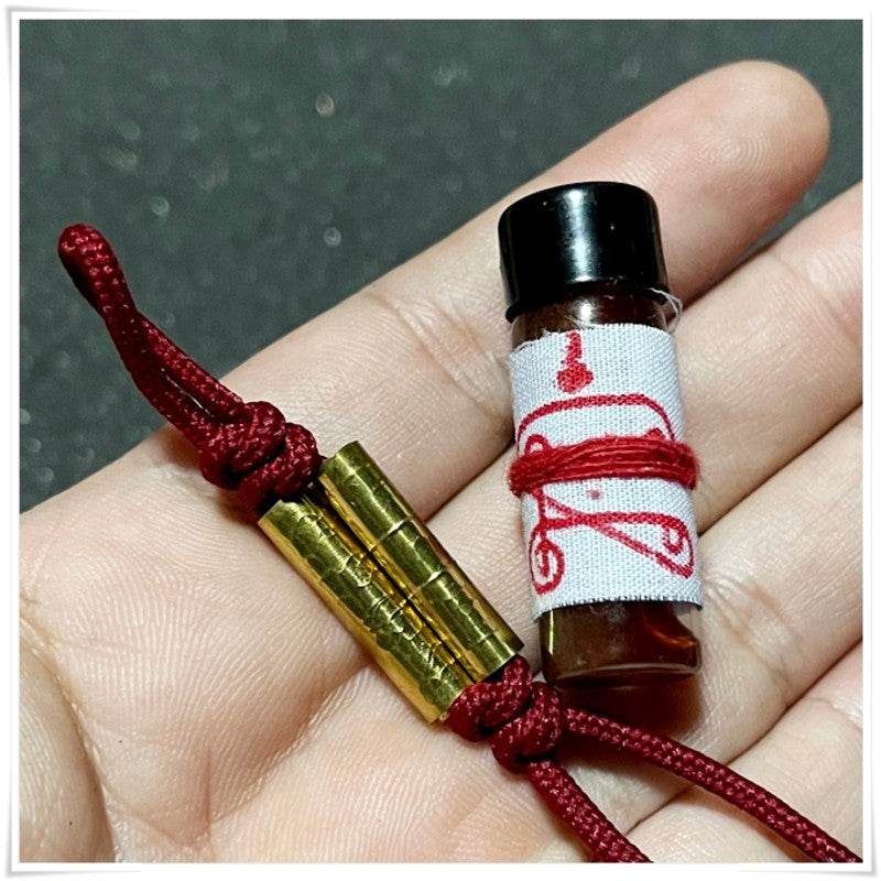Khmer attraction oil for love and luck in a small bottle with decorative cord and charms