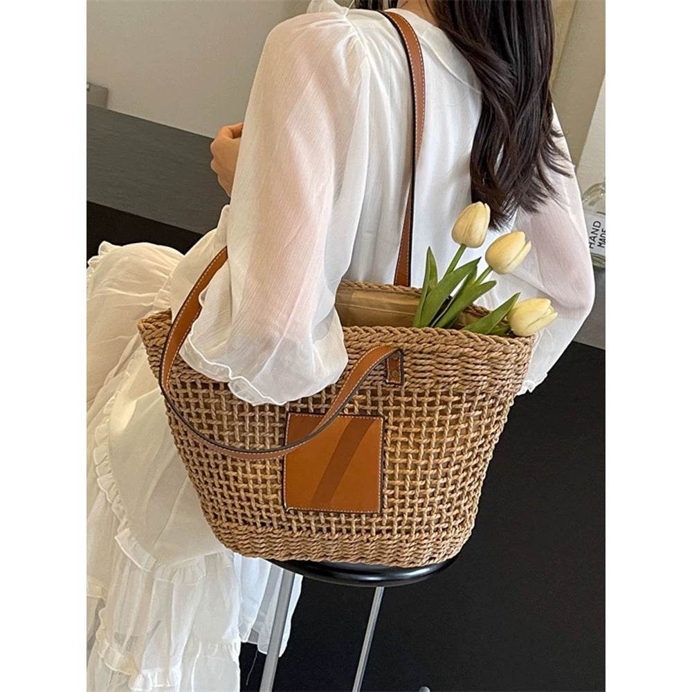 Korean style handwoven basket bag with brown leather straps carried by woman in white dress