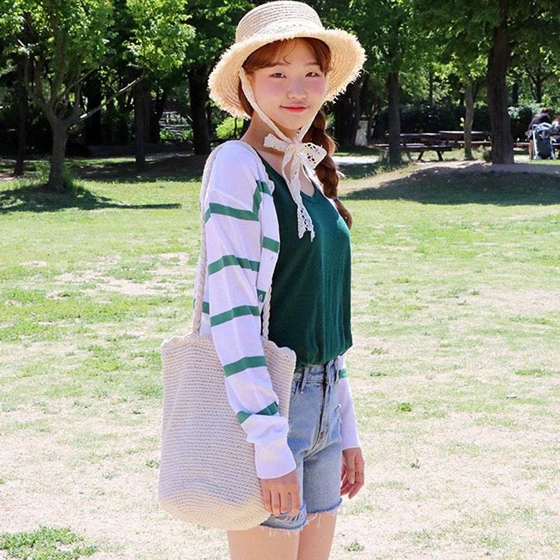 Woman wearing Korean style handwoven shoulder bag in a park with casual outfit and straw hat