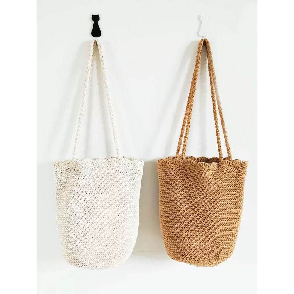 Two Korean style handwoven shoulder bags in white and brown hanging on wall hooks