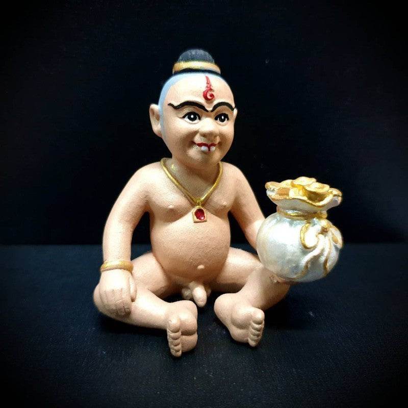 Kuman Thong amulet for business success depicting a small sitting figure with a gold pouch