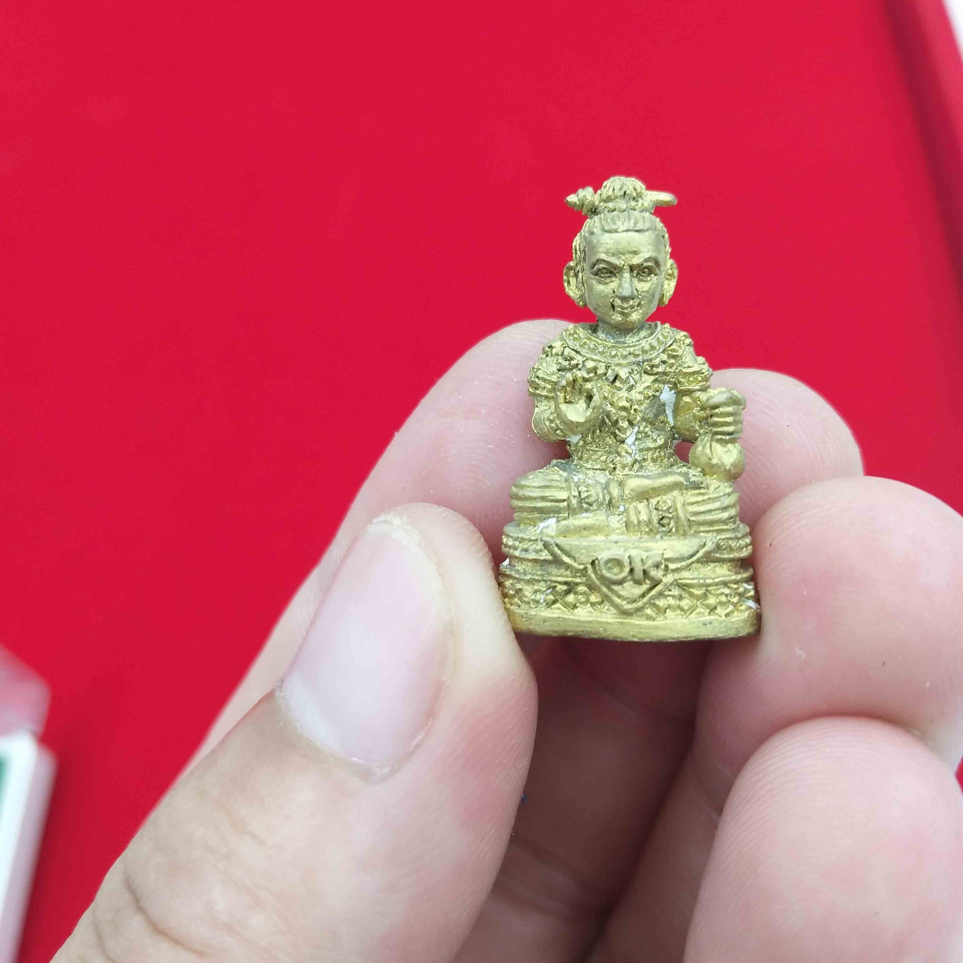 Kuman Thong amulet for prosperity held in a hand, showcasing intricate design and details for spiritual protection.