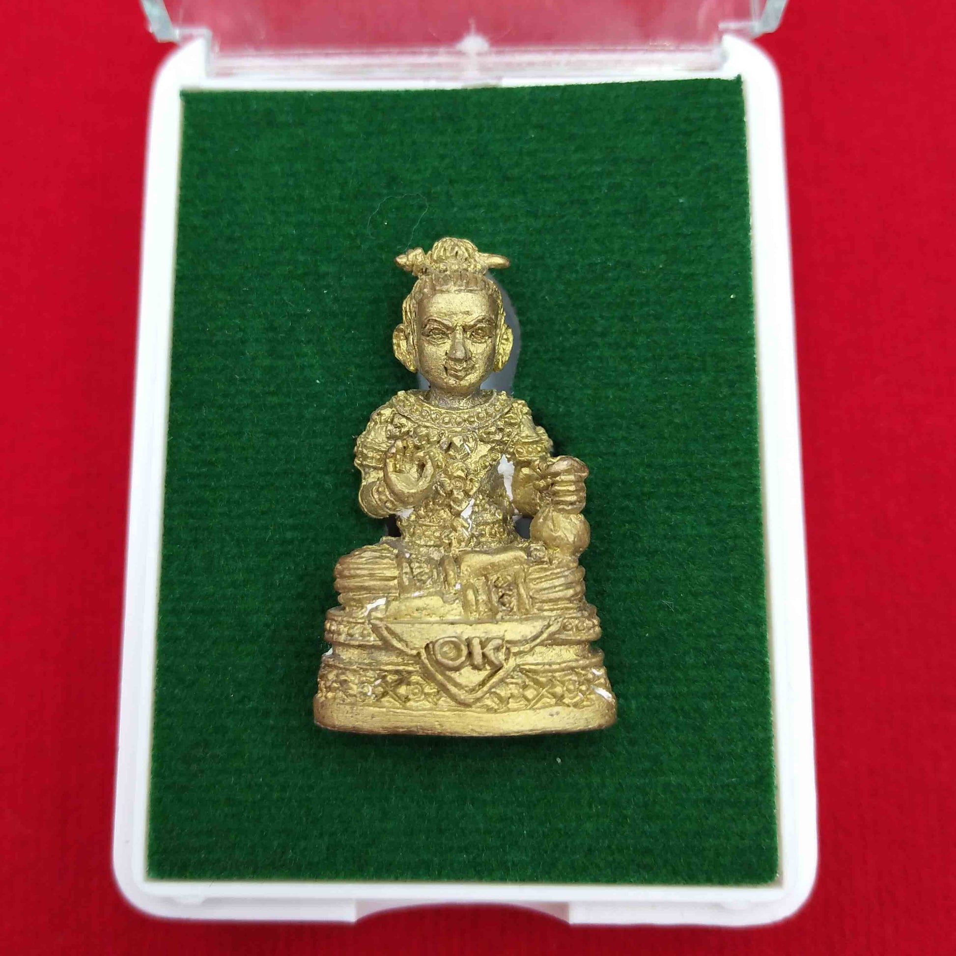 Kuman Thong amulet for prosperity displayed in a protective case with green felt background