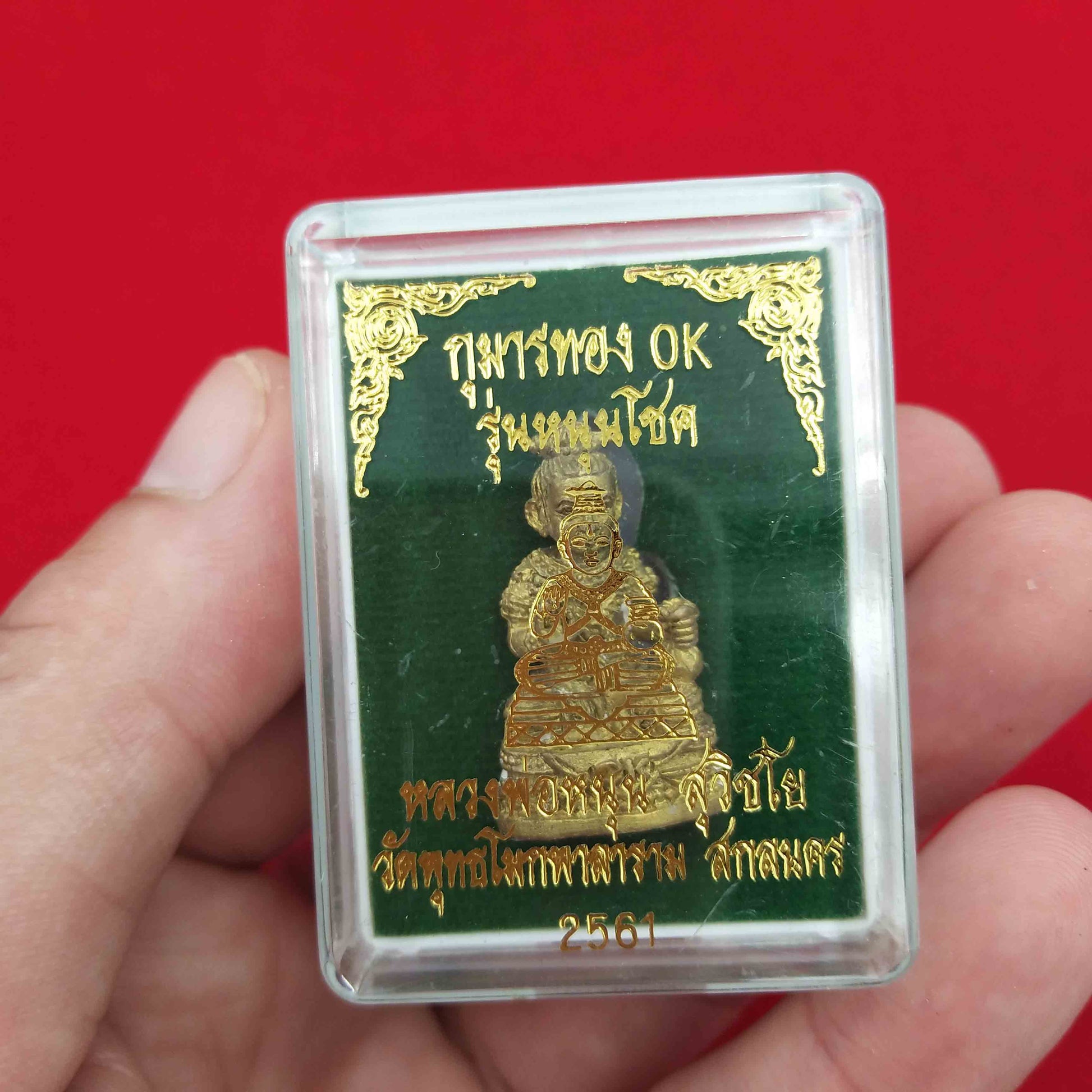 Kuman Thong amulet for prosperity in gold color, protected in a clear case for safe display.