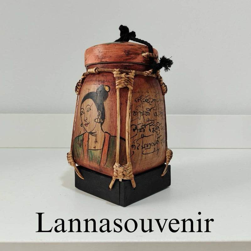 Lanna bamboo blessing box with traditional artwork and Thai script on a black stand from One-Sake.com