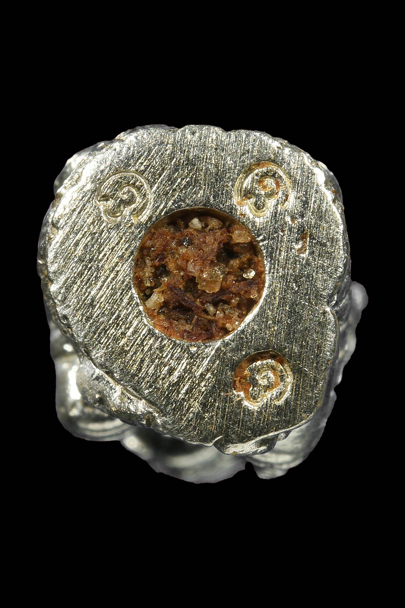 Lanna guardian wealth protection charm made of silver with intricate designs and a central garnet stone